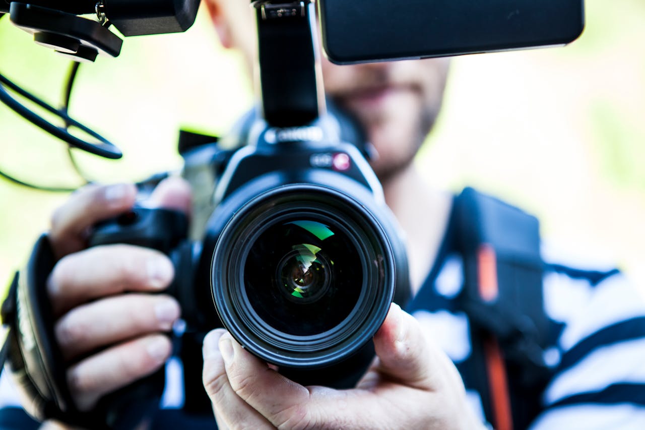 Services A close-up shot of a cameraman filming, focusing on the camera lens and equipment.